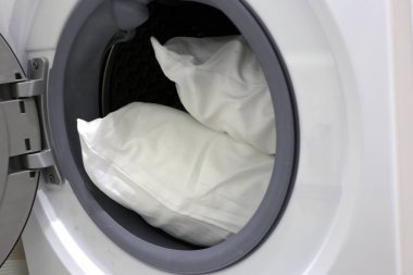Çamaşır makinesinde beyaz yastık.