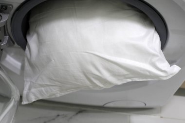 Çamaşır makinesinde beyaz yastık.