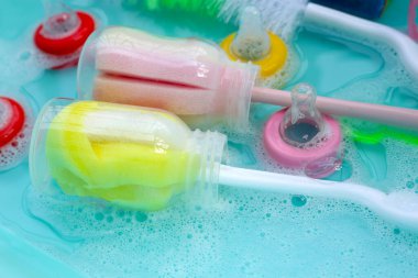 Bebek şişelerini plastik mavi leğende yıka.