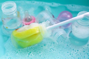 Bebek şişelerini plastik mavi leğende yıka.