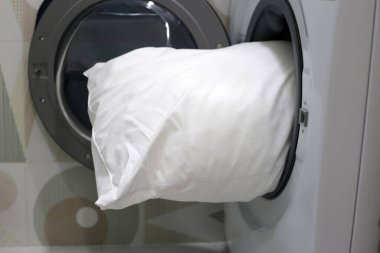 Çamaşır makinesinde beyaz yastık.