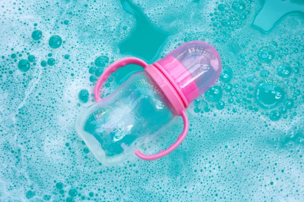 Sterilizing baby bottle in plastic blue basin