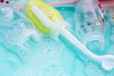 Bebek şişelerini plastik mavi leğende yıka.