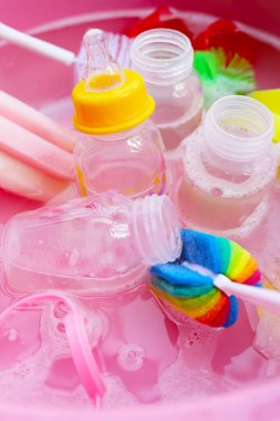 Bebek şişelerini plastik pembe leğende yıka.