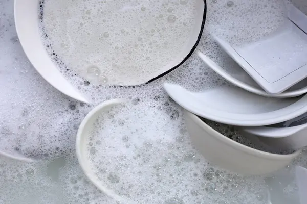 Dish washing, Dirty dishes soaking in kitchen sink.