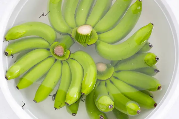 Raw green bananas soaking the bananas in water. Cleaning fruits