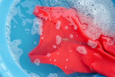 Kadın elbisesi, beyaz köpüklü çözünmüş deterjana batırılmış. Çamaşır konsepti