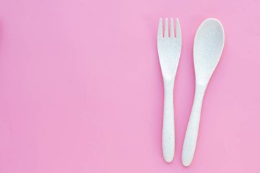Pembe arka planda kaşık ve çatal.