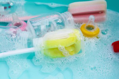 Bebek şişelerini plastik mavi leğende yıka.