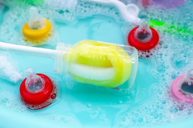 Bebek şişelerini plastik mavi leğende yıka.