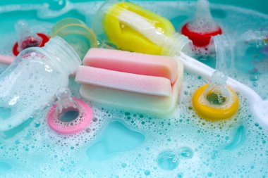 Bebek şişelerini plastik mavi leğende yıka.