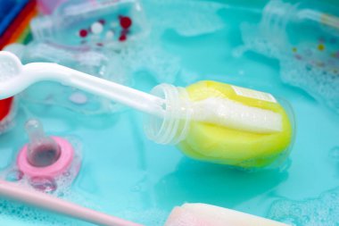 Bebek şişelerini plastik mavi leğende yıka.