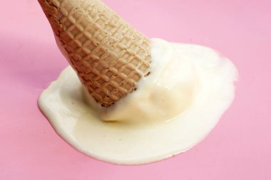 Pembe arka planda waffle külahı olan erimiş dondurma topu..