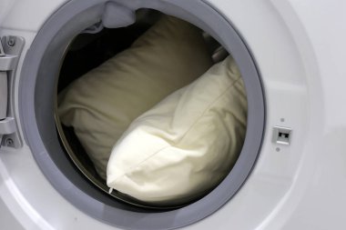 Çamaşır makinesinde beyaz yastık.