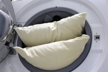 Çamaşır makinesinde beyaz yastık.