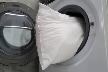 Çamaşır makinesinde beyaz yastık.