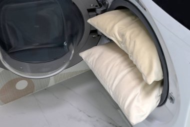 Çamaşır makinesinde beyaz yastık.
