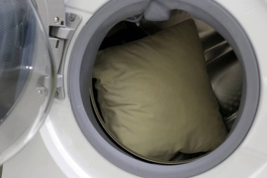 Çamaşır makinesinde beyaz yastık.