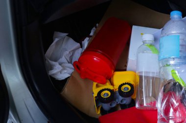 Eşyalarla dolu arabada, plastik torbalar, plastik su şişeleri, evrak dosyaları, kağıt torbalar, kağıt mendil..