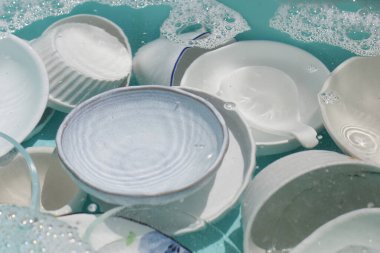 Dishes and bowls in water and bubbles of dishwashing liquid