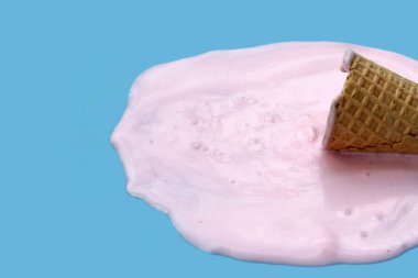 Mavi zemin üzerinde waffle külahı olan dondurma topu eritiliyor.