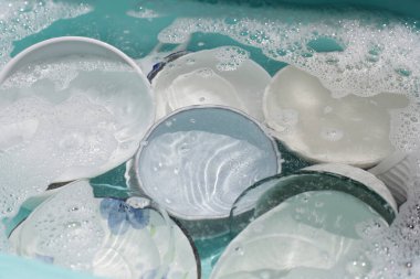 Dishes and bowls in water and bubbles of dishwashing liquid