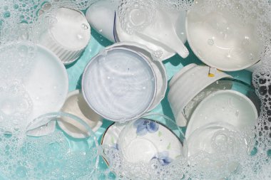 Dishes and bowls in water and bubbles of dishwashing liquid