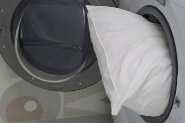 Çamaşır makinesinde beyaz yastık.