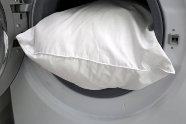 Çamaşır makinesinde beyaz yastık.