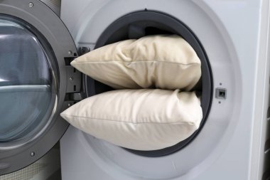 Çamaşır makinesinde beyaz yastık.