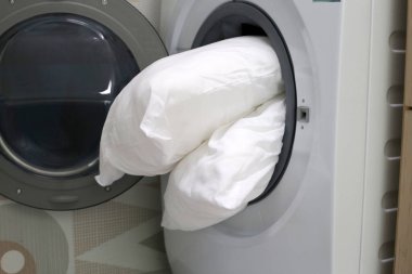 Çamaşır makinesinde beyaz yastık.