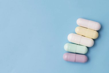 Mavi arka planda renkli kapsüller ve haplar.