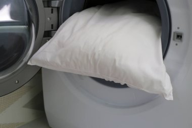 Çamaşır makinesinde beyaz yastık.