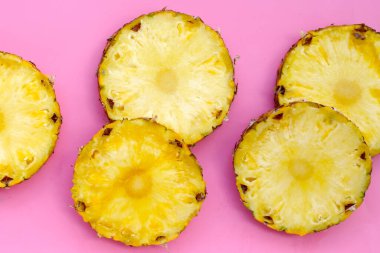Olgun ananas dilimleri, pembe arka planda taze meyve..