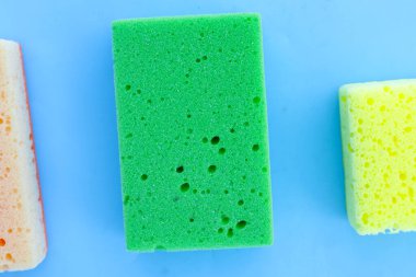 Mavi arka planda bulaşık yıkama süngeri.