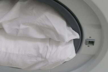Çamaşır makinesinde beyaz yastık.
