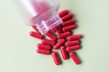 Beyaz arka planda kırmızı Astaxanthin ek kapsülleri.