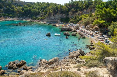 Turistler Yunanistan 'ın Rodos adasındaki Anthony Quinn koyunda yüzüyorlar. Bu plaj adanın en popüler koylarından birinde yer almaktadır..
