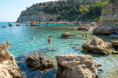 FALIRIKI, GREECE - 09 Eylül 2024: Turistler Yunanistan 'ın Rodos adasındaki Anthony Quinn körfezinde yüzüyorlar. Bu plaj adanın en popüler koylarından birinde yer almaktadır..
