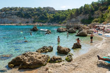 FALIRIKI, GREECE - 09 Eylül 2024: Turistler Yunanistan 'ın Rodos adasındaki Anthony Quinn körfezinde yüzüyorlar. Bu plaj adanın en popüler koylarından birinde yer almaktadır..