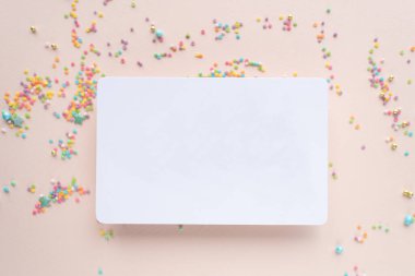white paper mockup with texture on festive peach background with confetti, invitation mockup, top view