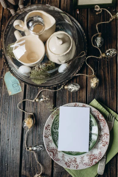 木製の背景に白い紙のシートイースターテーブル イースターの装飾とカードのモックアップ — ストック写真