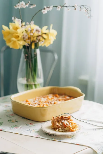 美味的自制糕点在黄色的烤盘里 背景是黄色的春花 厨房明亮 — 图库照片