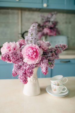 Mutfaktaki masanın üzerinde bir buket çiçek, mutfak tasarımı, mavi renk.