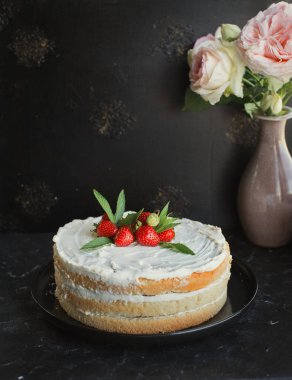 Siyah arka planda kremalı ve çilekli bisküvi keki.