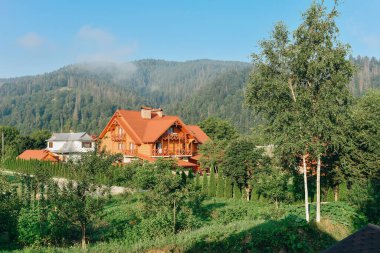 Yaz tatilleri dağlarda, ormandaki ahşap bir ev dağların arka planında.