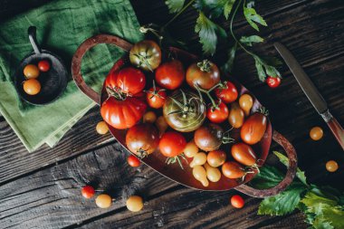 Durgun hayat, farklı domates çeşitleri ahşap bir masaya saçılmış, yumuşak sabah ışığı, üst görünüm