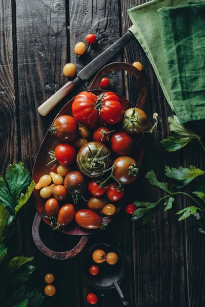 Durgun hayat, farklı domates çeşitleri ahşap bir masaya saçılmış, yumuşak sabah ışığı, üst görünüm