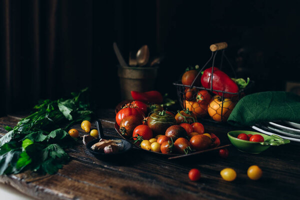 Still life, different varieties of tomato scattered on a wooden table, soft morning light, top view