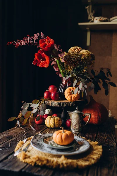 Autumn festive dinner in a rustic style, decorated with flowers and vegetables on a dark background